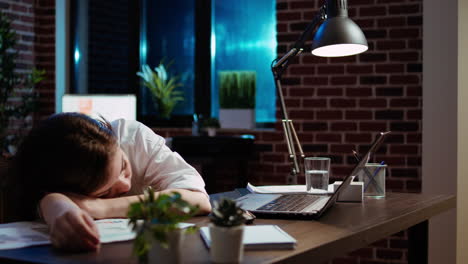 empleado somnoliento durmiendo en el escritorio de la computadora tarde en la noche en la oficina de pared de ladrillo