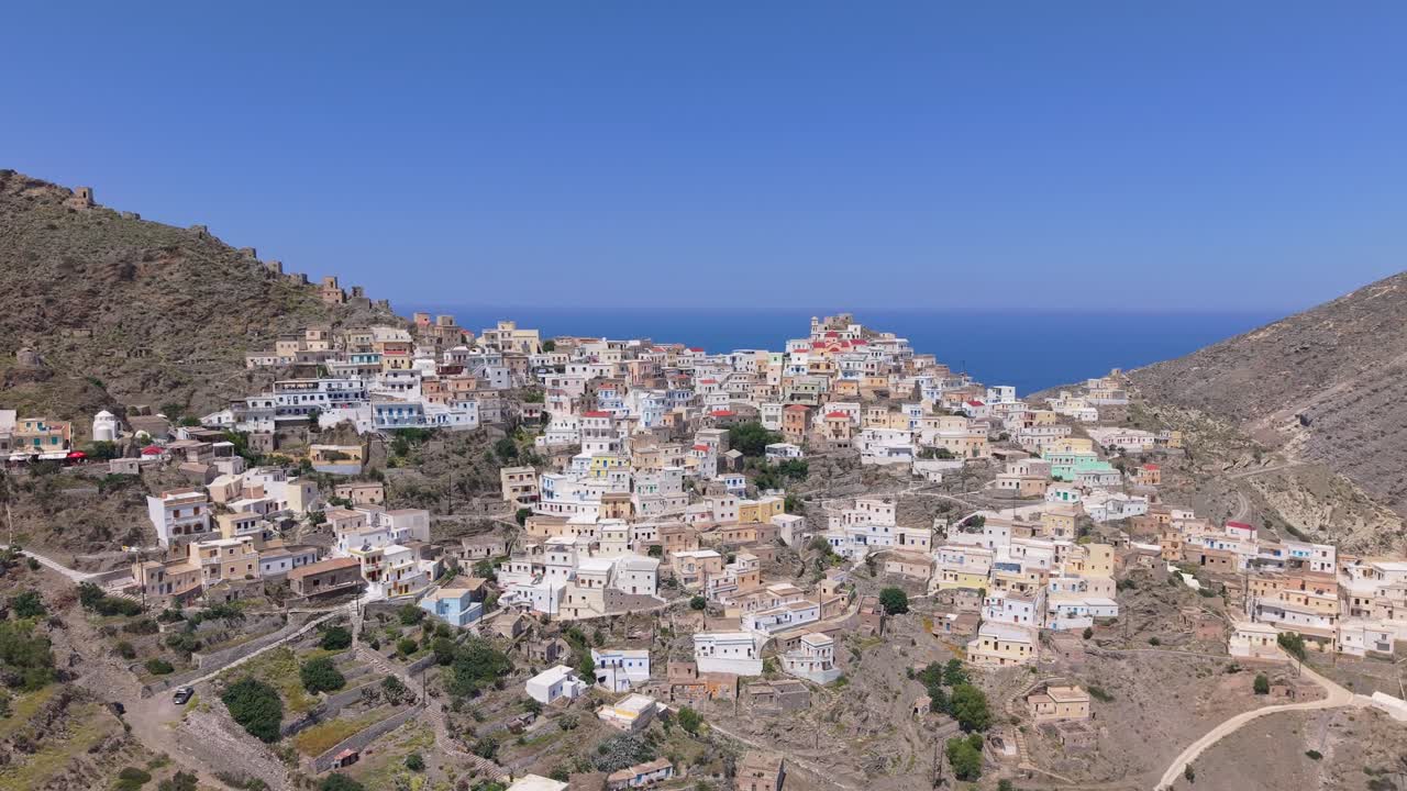Panoramic drone shot capturing Olympos Mountain, the traditional village, and the Aegean Sea on Karpathos Island, highlighting stunning landscapes and Greek island charm