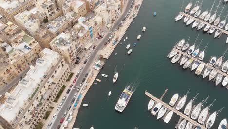 bird's-eye, panning aerial 4k drone footage, of a marina along a water channel between two mediterranean cities of malta