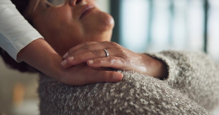 Young Person Comforting Senior Woman with Hand on Shoulder