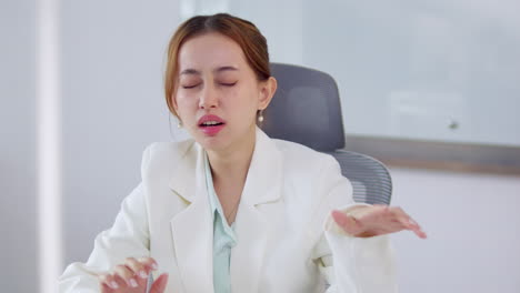 a businesswoman yawns at her desk highlighting the challenges of work fatigue in a professional setting.