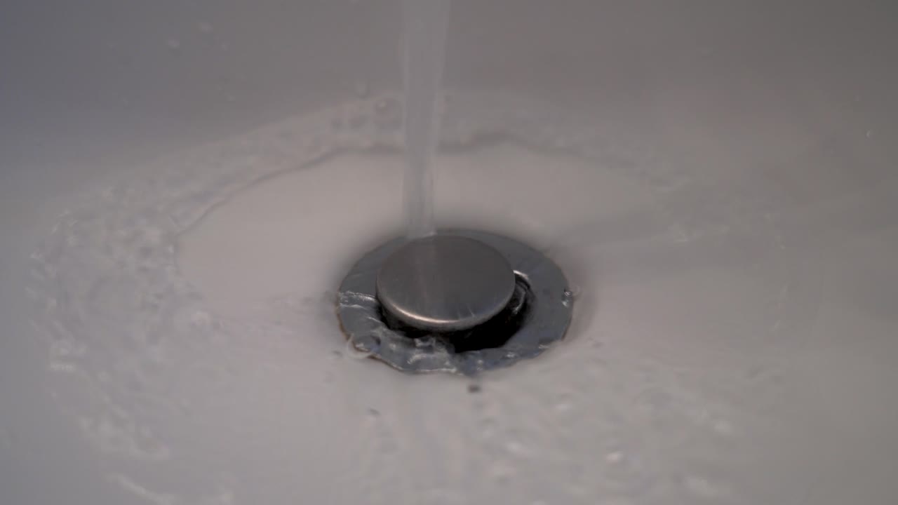 A closeup shot of running water draining from a bathroom sink.