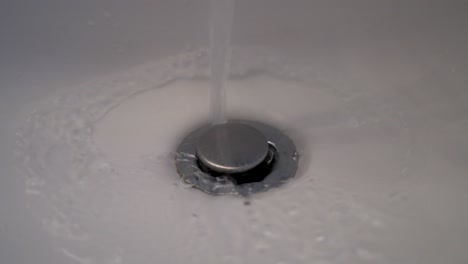 a closeup shot of running water draining from a bathroom sink.