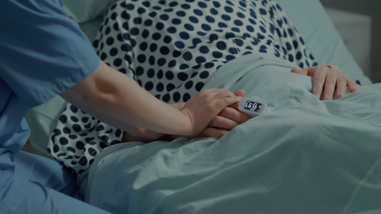 Close up of nurse comforting ill patient in hospital ward