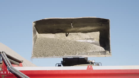 Slow-Motion-Detail-of-Front-Loader-Bucket-Pouring-Limestone-into-Dump-Truck