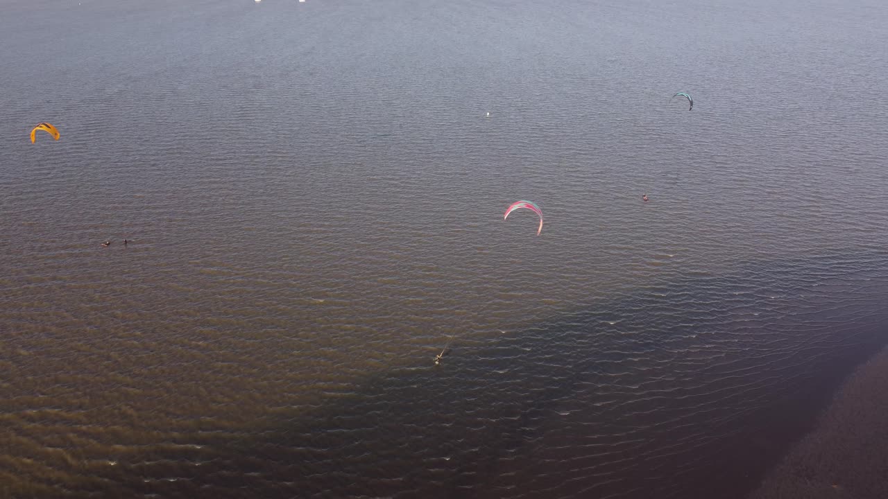 toma de órbita aérea de kitesurfistas surfeando en el río de la plata cerca de vicente lópez durante el día soleado