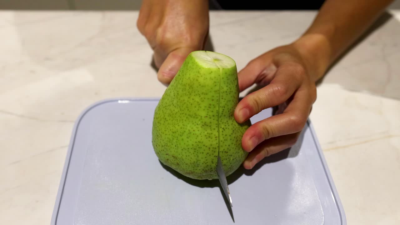 persona cortando una pera con un cuchillo