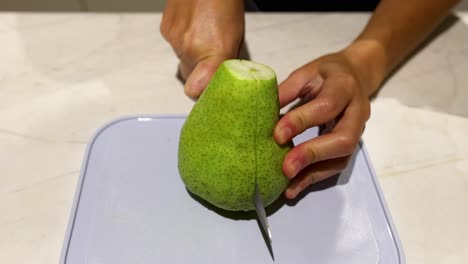 person slicing a pear with a knife