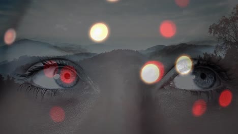 glowing spots of light over close up of female eyes against landscape with mountains