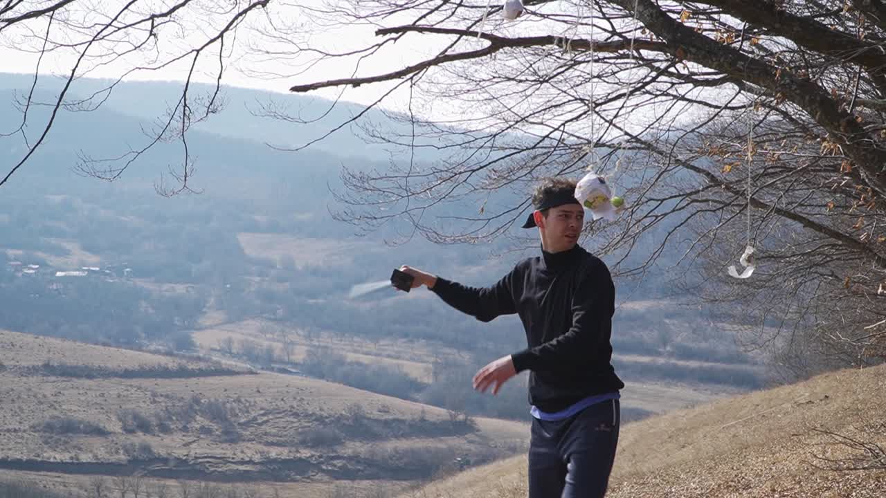 A skilled martial artist practices with his katana on a scenic hillside, striking targets hanging from tree branches. Dynamic, precise, and captivating for martial arts enthusiasts.