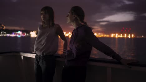 silhouette of two attractive young women traveling on a ship at night. girlfriends on the boat