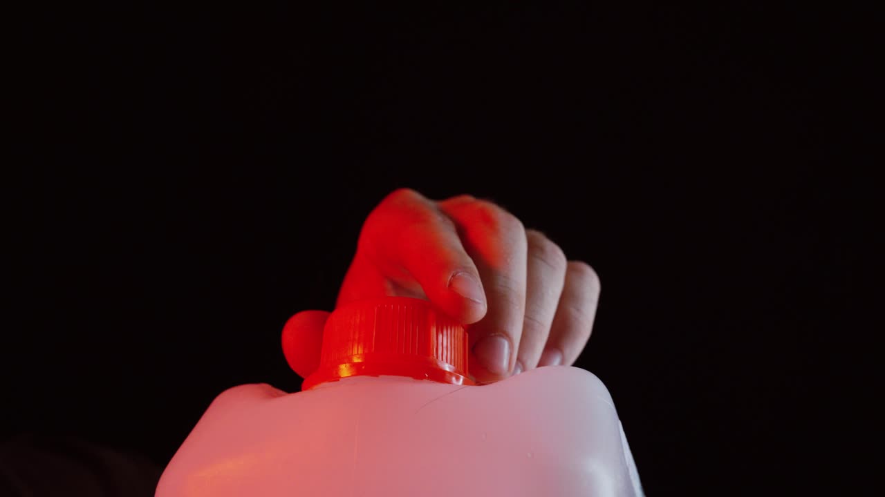A person opens the cap of a chemical canister, symbolizing the risk of poisoning or exposure to toxic substances. Ideal for health, safety, or environmental awareness themes