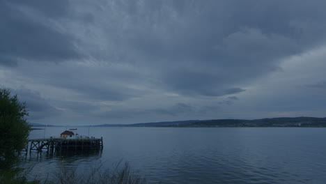 Timelapse-Del-Muelle-Y-El-Mar-Y-El-Cielo-Y-La-Ciudad-Distante,-Las-Nubes-Vienen-Corriendo