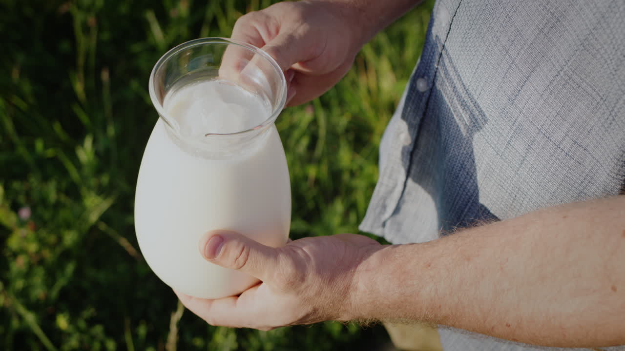 un hombre sostiene una jarra de leche en un prado verde 1