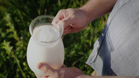 A-man-holds-a-jug-of-milk-in-a-green-meadow-1