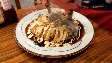 Okonomiyaki,-professional-cutting-Japanese-teppan-cuisine-in-a-traditional-Japanese-restaurant-in-Hong-Kong