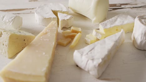 video of assorted hard and soft cheeses on rustic white wooden table top