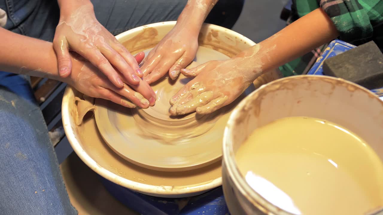 Woman and boy make plate on pottery wheel in workshop