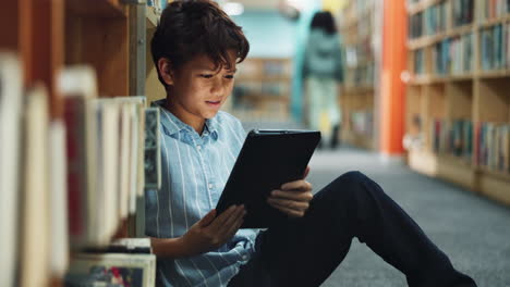 boy reading on a tablet in a library