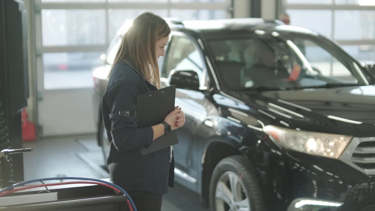 gerente femenina discutiendo la reparación de vehículos con el mecánico en el taller de reparación de automóviles