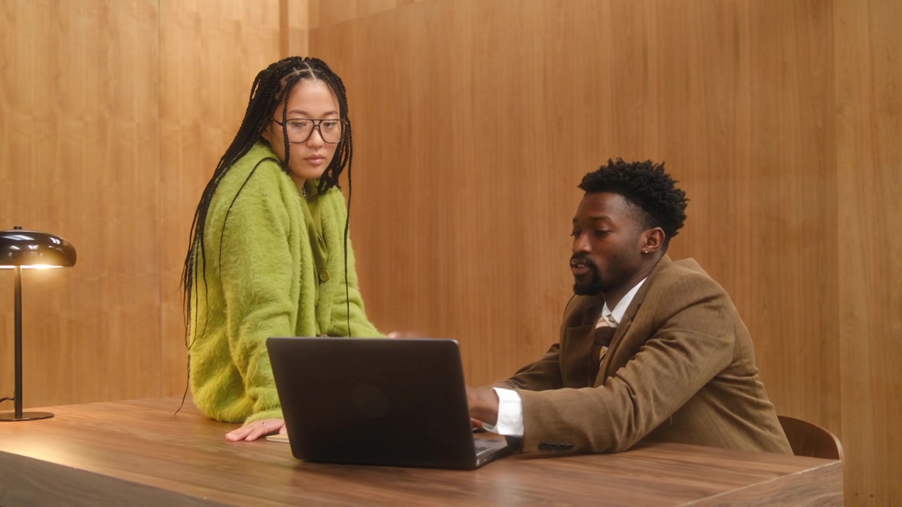 Multiethnic Business Professional Using Laptop and Talking in Office