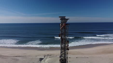 toma aérea en órbita de la torre en la playa de arena de praia de mira durante un hermoso día soleado con el océano azul como telón de fondo