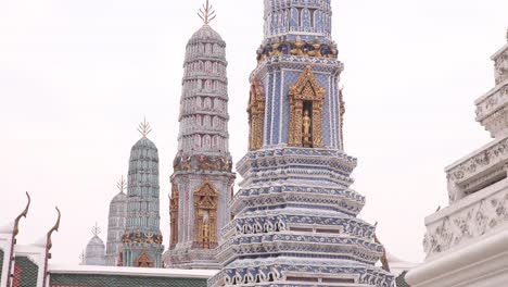 looking-up-at-towering-detailed-pagoda-spires-in-a-buddhist-temple-complex-in-the-Rattanakosin-old-town-of-Bangkok,-Thailand