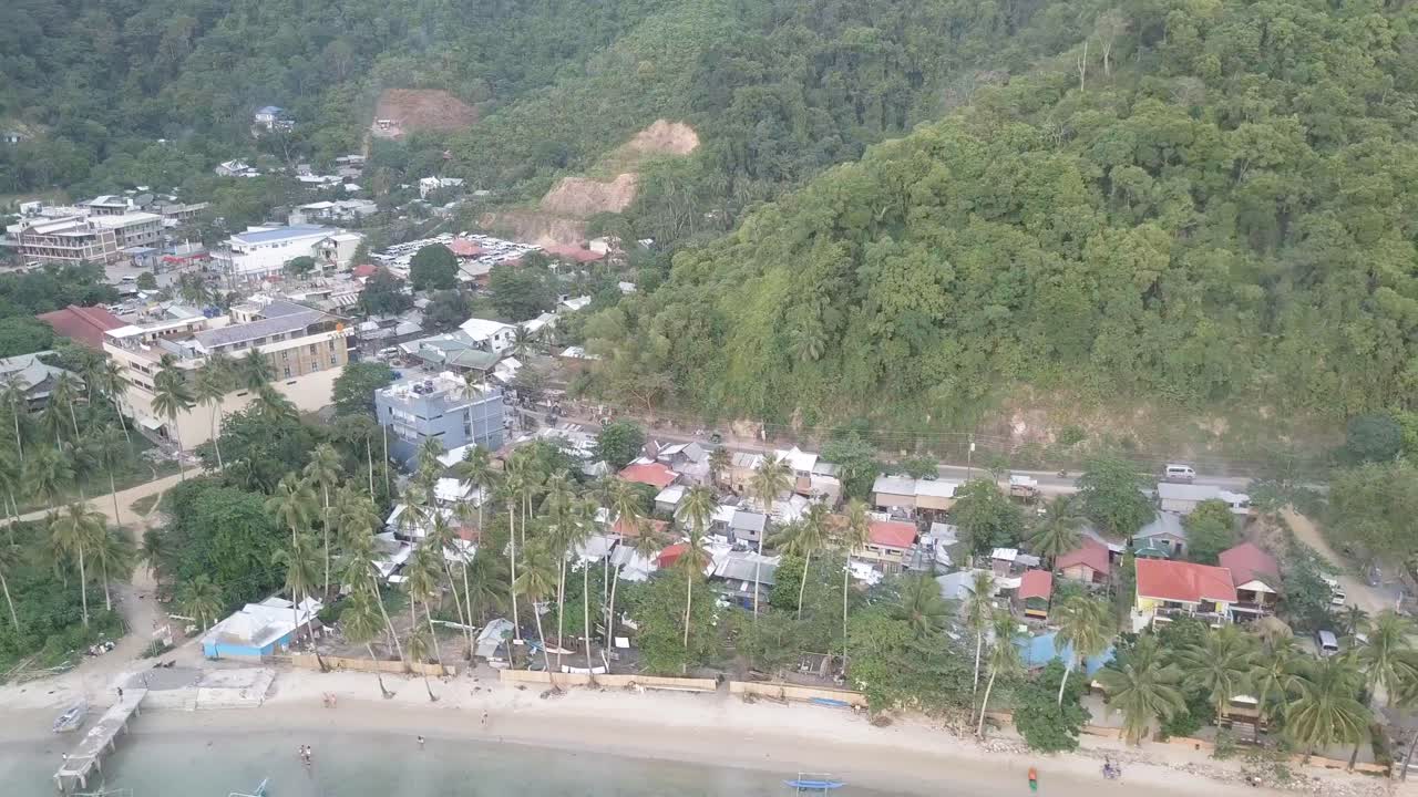 toma aérea de drones de 4k frente a la playa en la playa de corong corong con automóviles y motocicletas que pasan por la carretera detrás en el nido, palawan, filipinas