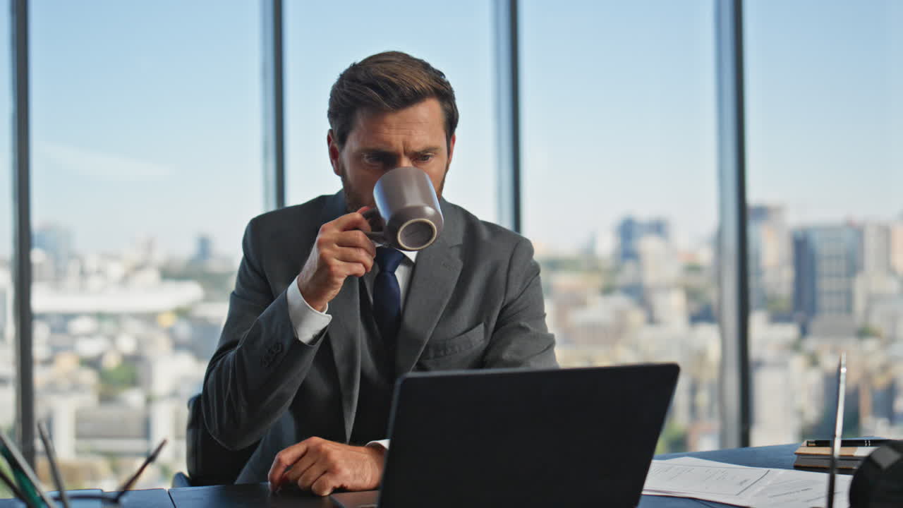 Leader maturo che fa una chiamata al laptop bevendo caffè al mattino. Uomo pensieroso che parla.
