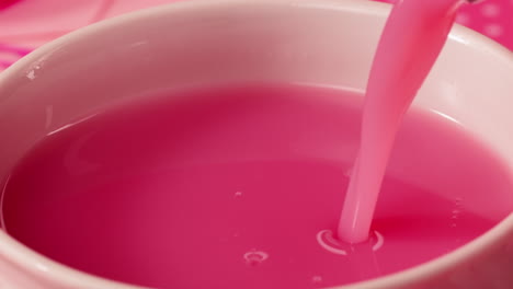 pink liquid being poured into a bowl