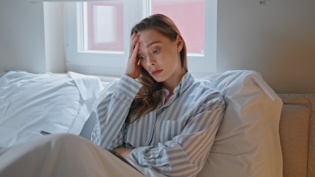 Worried student studying bed at white apartment closeup. Woman looking tablet