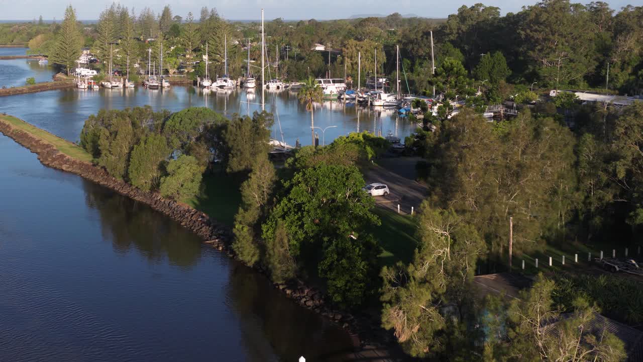 Aerial footage captures tranquil marina with boats, lush greenery, and calm waters in Brunswick Heads, NSW, Australia
