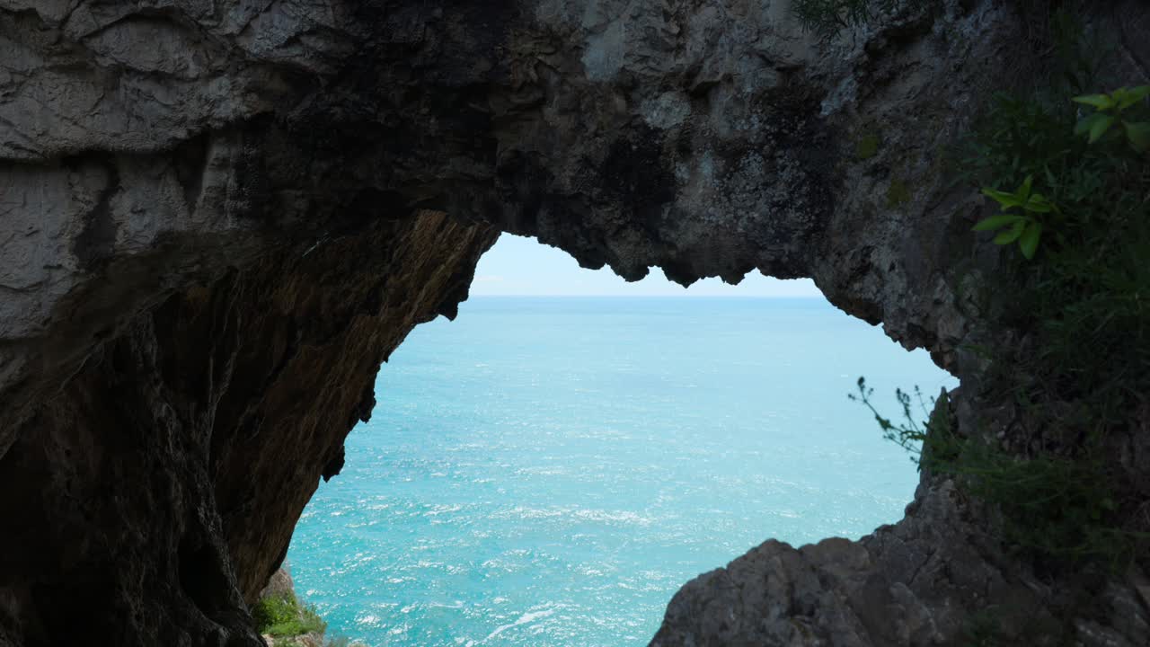 View of Mediterranean Sea from inside Grotta dei Falsari, Cave of Forgers, rock formations and coastline, Noli, Italy