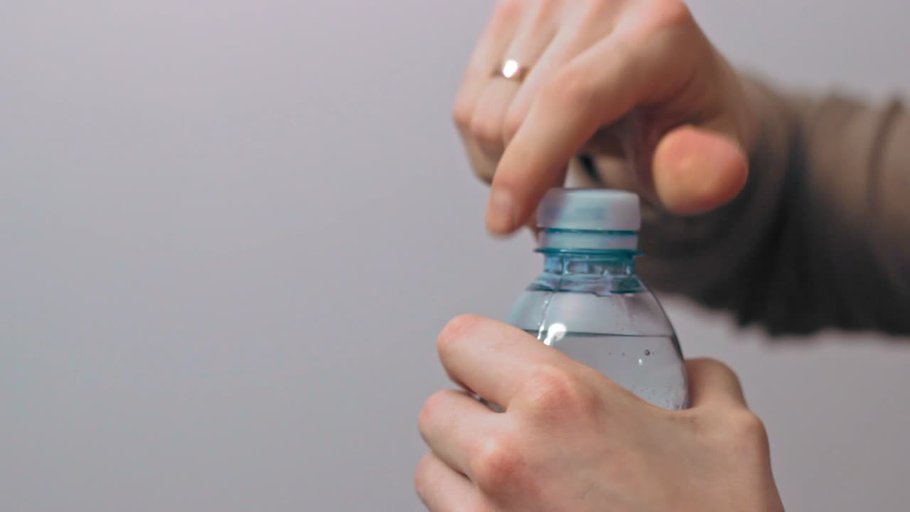 hombre abriendo la tapa de la botella de agua de plástico de cerca