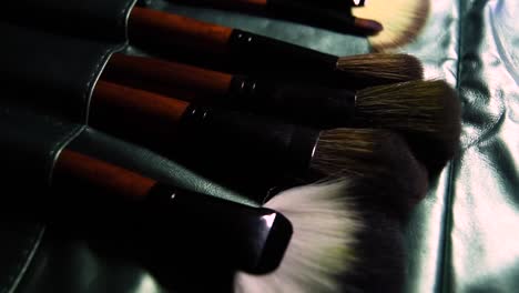 wooden-and-metal-brown-set-of-make-up-brushes-on-green-shiny-cover-background-with-sliding-movement