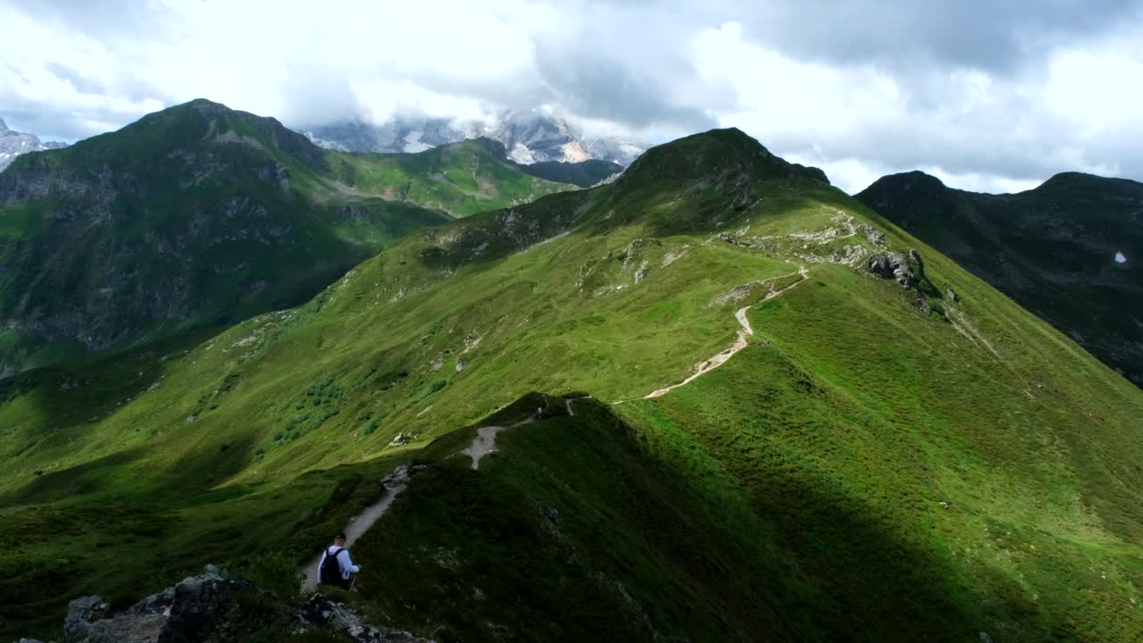 A panoramic view of winding trails across green mountain ridges with a cloudy sky backdrop. Ideal for hiking, trekking, and exploring scenic natural landscapes.