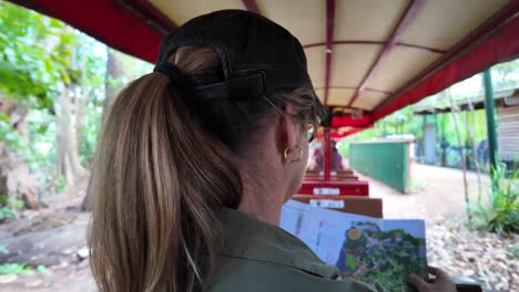 women riding on a sightseeing adventure train reading a map while traveling through a tropical location