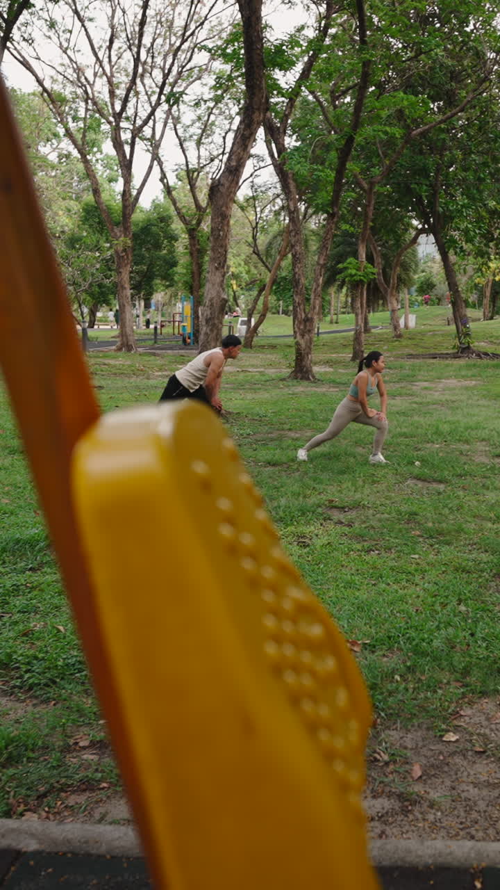 Homem e mulher alongando e se exercitando num parque verde