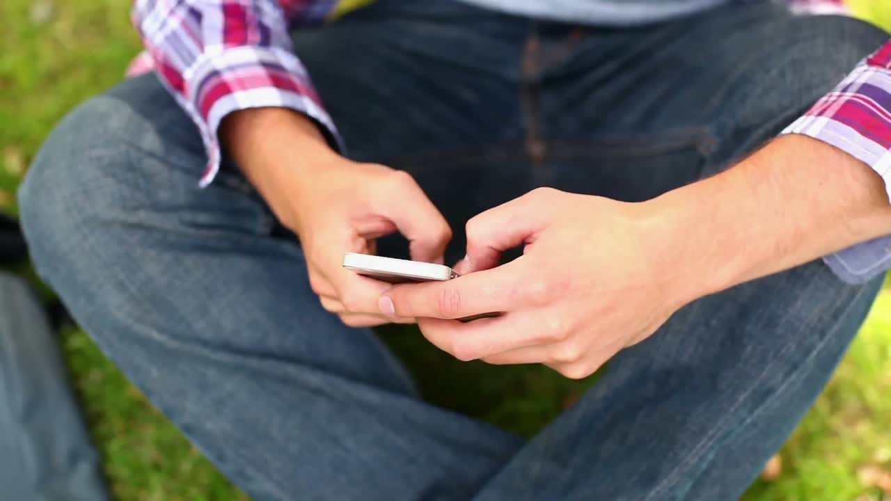 밖에서 앉아서 전화로 문자를 보내는 학생