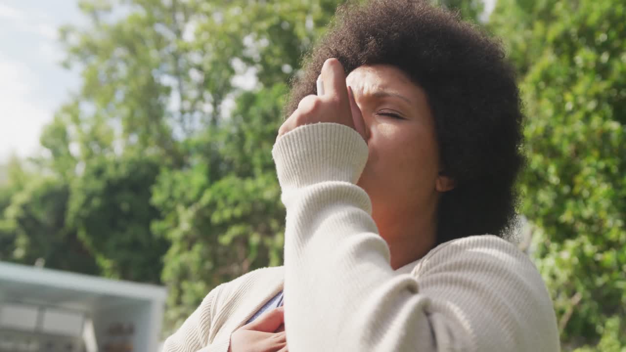 Video of plus size african american woman using inhalator outdoors