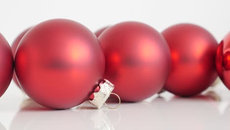 baubles in red matte color on white reflective surface slow tilt 4k footage