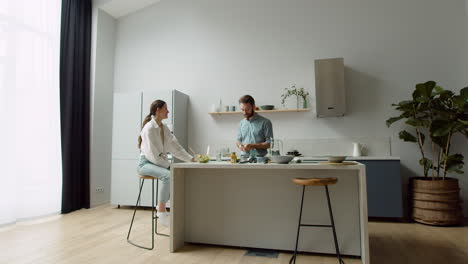 pareja alegre charlando y preparando una sabrosa ensalada en una cocina moderna 2