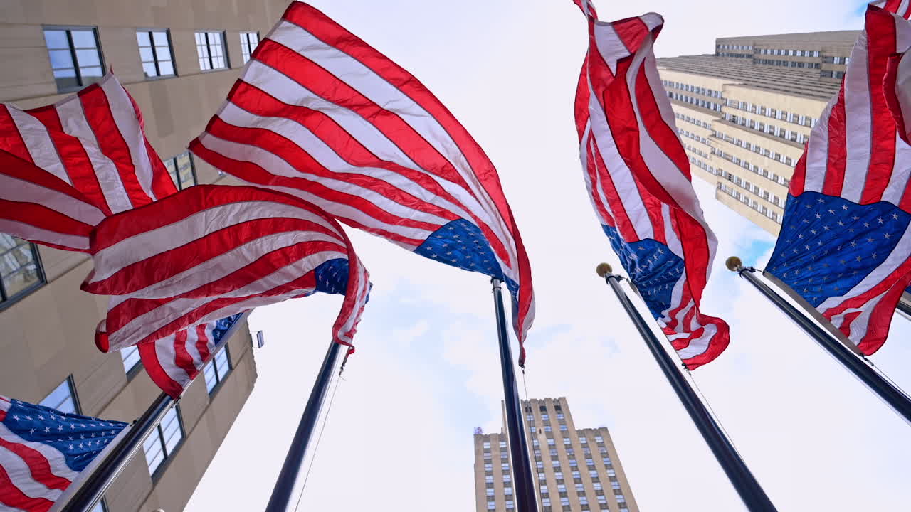Bandiere americane che sventolano al vento. Vista dal basso dei simboli patriottici in una strada di New York. Grattacieli sullo sfondo