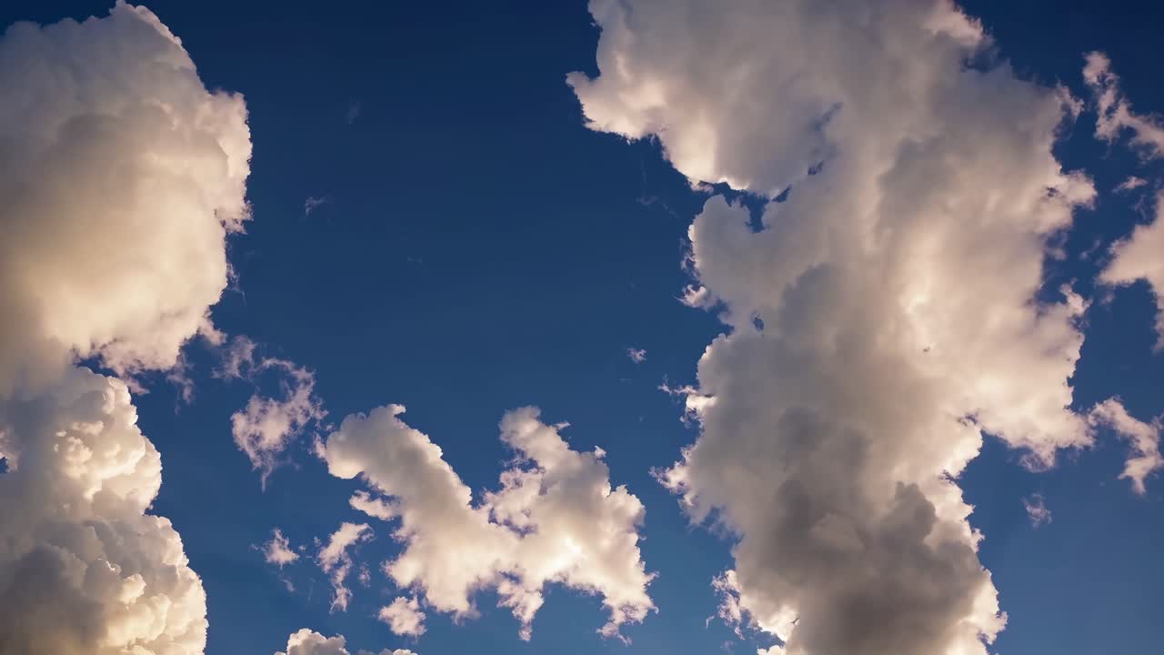 Un vídeo sereno muestra nubes esponjosas contra un cielo azul intenso, visto desde un ángulo bajo.
