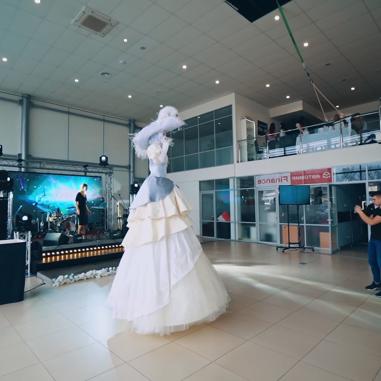 Show room. Woman in carnival costume in a luxury salon. People gathering in the hall before the presentation.