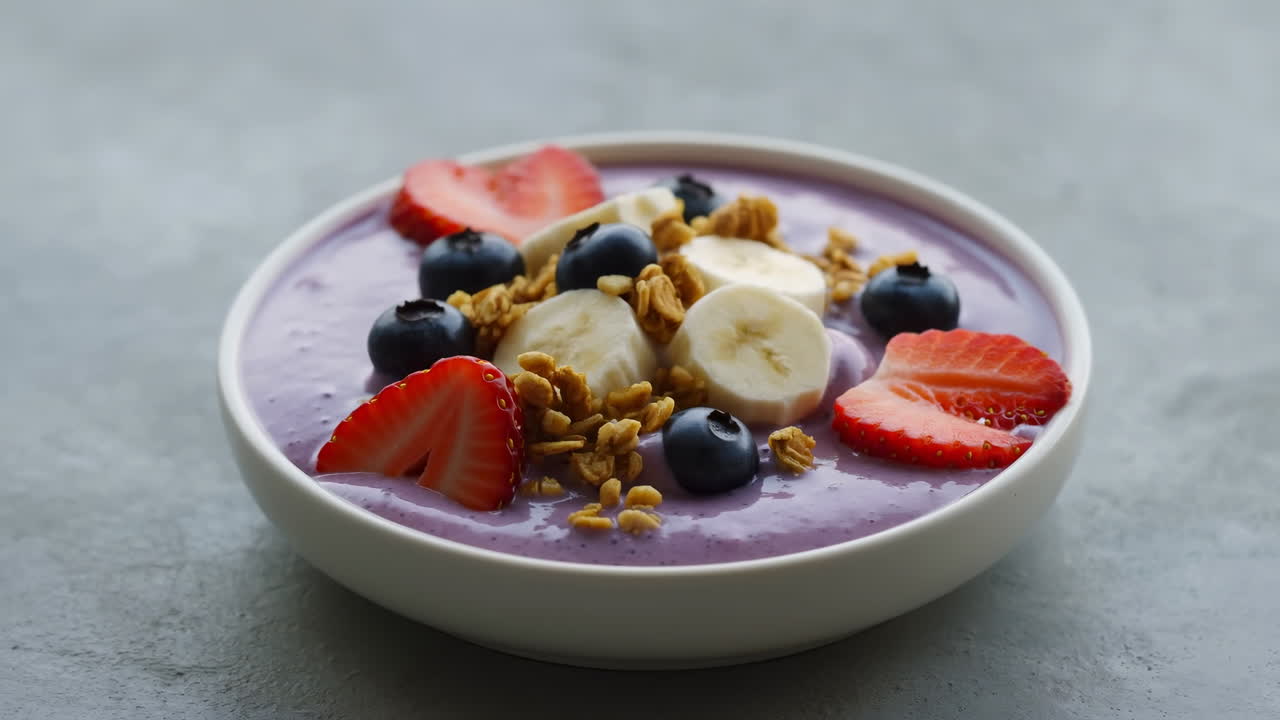 Smoothie bowl salutare guarnita con frutti di bosco freschi, banana e granola