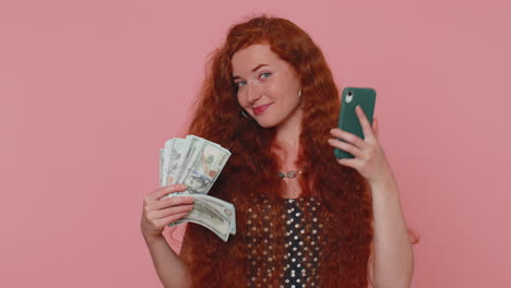 Happy-redhead-woman-looking-smartphone-display-sincerely-rejoicing-win,-receiving-money-dollar-cash