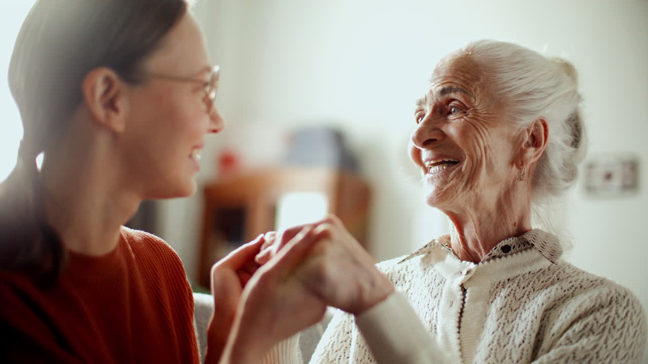 Elderly Woman Holding Hands with Granddaughter during Heartwarming Conversation
