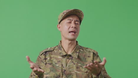 close up of wondering asian man soldier saying why and standing doubtfully in the green screen background studio