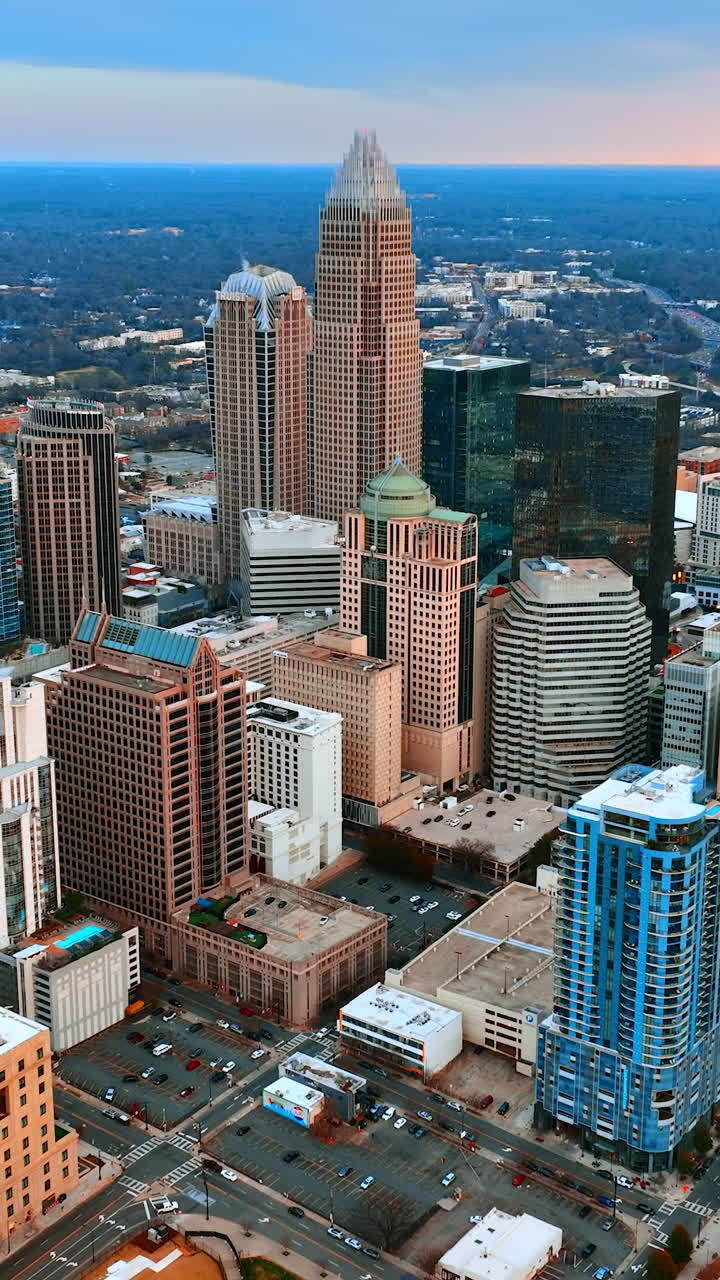 Volando più vicino all'architettura di grattacieli nell'uptown di Charlotte, Carolina del Nord, USA. Vasto paesaggio con molta vegetazione sullo sfondo. Video verticale.